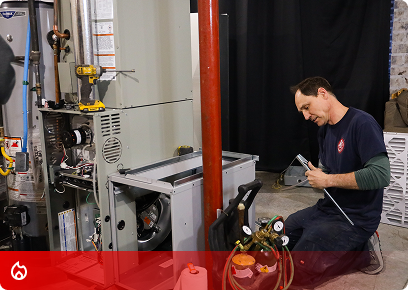KB Complete technician kneeling to service a furnace with a gauge set